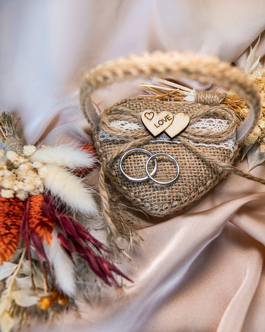 Hochzeitsringe, Liebe Dekorationen und Brautaccessoires in einem rustikalen Korb auf Seidenschleier.